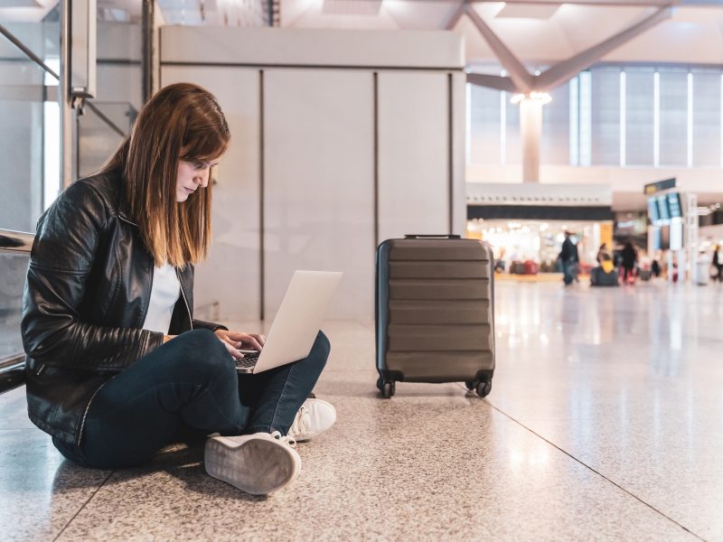 Young Woman With Her Baggage And Her Laptop Waiting At The Airport Concept Of Travel And Vacation